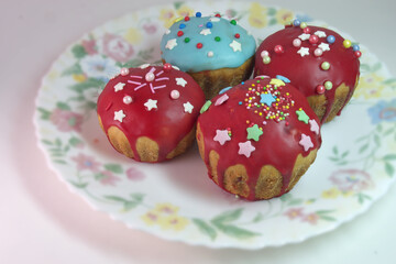 sweet Easter bread. homemade muffins, with melted sugar dark red glaze topping, decorated with sprinkles and colored sugar stars. on exquisite plate
