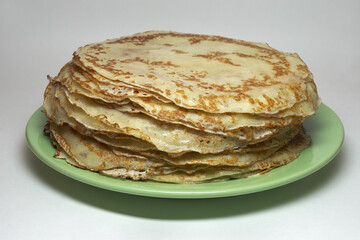 blynchyky stacked on green plate, traditional for Crepe week festive. round thin dough products, on milk and eggs. fried on pan