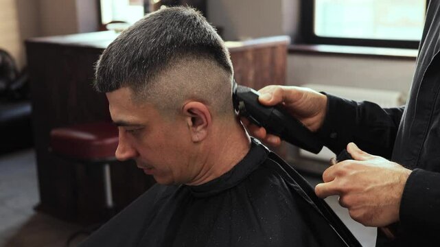 A skilled hairdresser is performing a precise haircut on a client in an upscale barbershop. The atmosphere is relaxed as the barber makes intricate cuts for a perfect finish