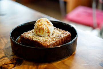 Fresh bread butter toast with Vanilla flavor ice cream on black ceramic plate on wooden table.