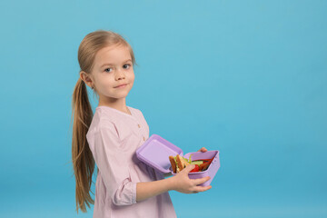 Cute little girl with lunch box on light blue background. Space for text