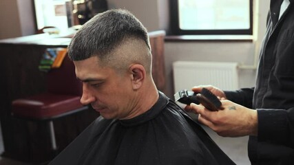 A skilled hairdresser is crafting a precise haircut for a client in a contemporary barbershop. The environment is relaxed, showcasing the artistry of haircutting with attention to detail and style