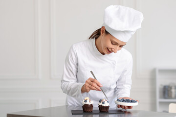 Confectioner decorating cupcake with blueberry in kitchen