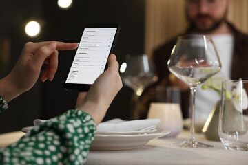 Couple choosing dishes from digital menu at restaurant, closeup