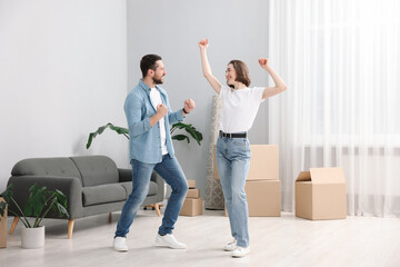 Moving day. Happy couple dancing in their new home