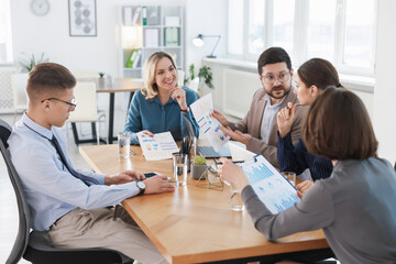 Coworkers working together at wooden table in office
