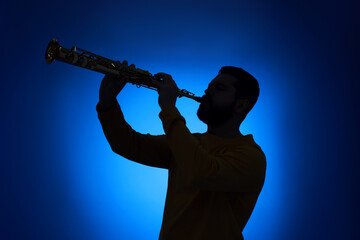 Professional musician playing soprano saxophone on blue background, backlit