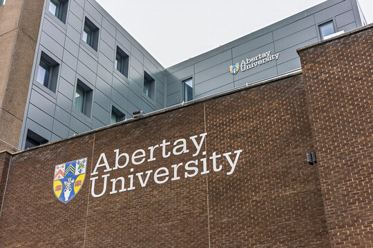 DUNDEE, UK - March 22, 2025: Modern Campus Building of Abertay University with Shield and Signage on Brick Wall and Side of Upper Wall