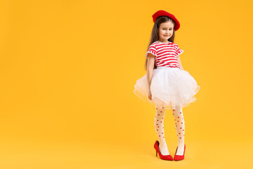 Stylish little girl wearing oversized high heeled shoes on orange background, space for text