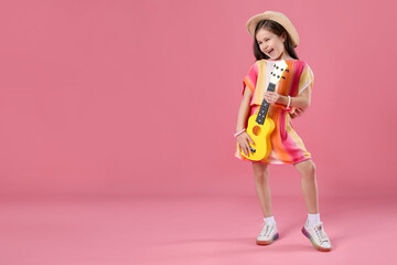 Cute girl playing toy guitar on pink background