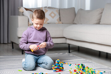 Cute boy playing with building blocks on floor at home. Space for text