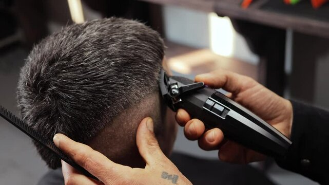 A hairdresser skillfully cuts hair using clippers in a contemporary barbershop. The focus is on precision and style as the client enjoys the transformation