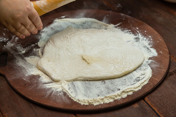 rolled out dough on a round board sprinkled with flour on a wooden table