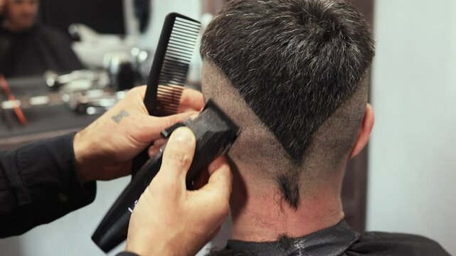 Hairdresser expertly performs a unique haircut design in a trendy barbershop. The client receives precise detailing as the stylist uses clippers and comb to achieve a fresh look