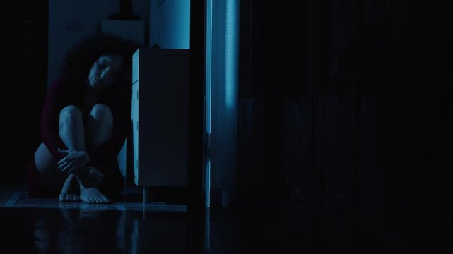 A frightened woman dashes through a corridor, running from an unknown danger. The mix of warm and cold light adds intensity.