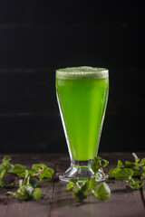 Fresh Lemon Mint Juice served in a tall glass with fresh mint leaves on a dark background and a wooden table side view of refreshing and healthy citrus beverage