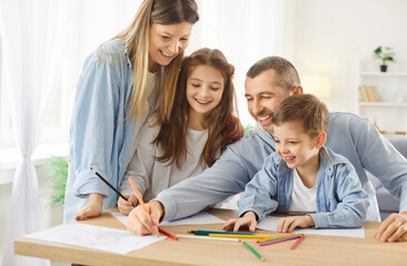 Loving family fun at home, father, mother, parents have fun painting, drawing together, happy playful dad, mum drawing in album paper with excited small boy, girl child on weekend as hobby amuse