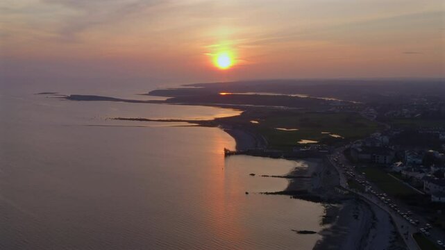 aerial vista of Galway Bay's shoreline bathed in golden sunset light over calm waters.