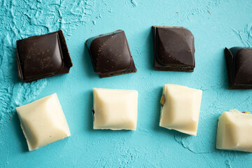 white milk chocolate, dark chocolate and dates on blue background in close-up