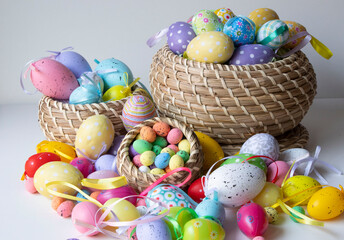 Colorful Easter eggs on the table and in brown wicker baskets. Lots of colorful eggs, a very pretty Easter background.