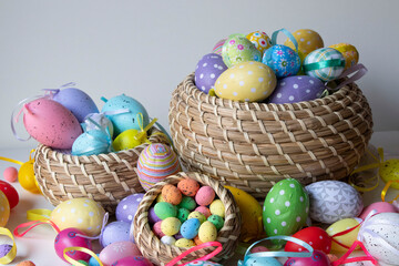 Colorful Easter eggs on the table and in brown wicker baskets. Lots of colorful eggs, a very pretty Easter background.