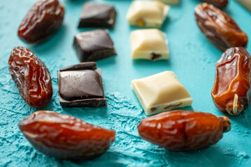 white milk chocolate, dark chocolate and dates on blue background in close-up