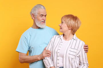 Lovely senior couple looking at each other on orange background
