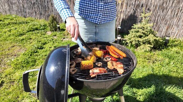 White male grilling assorted vegetables and meats on barbecue, outdoor cooking, summer picnic, Labor Day celebration, backyard gathering