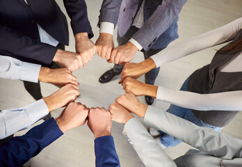 Close up top view of business team forming circle with fists, symbolizing unity and teamwork. Group...