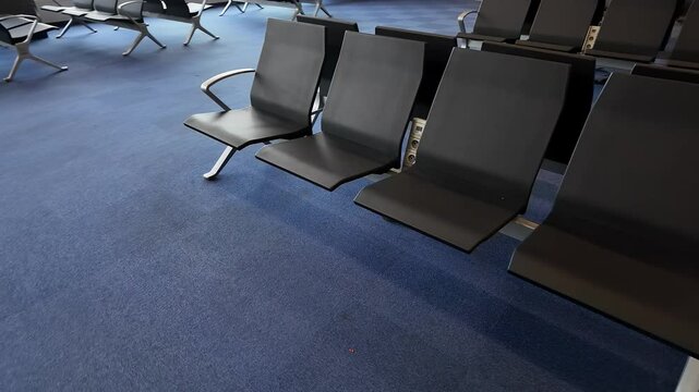 Empty black airport seating on blue carpet evokes travel anticipation, modern design, waiting area for global adventures
