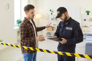 Detective or policeman collects evidence and records testimony from a witness at a crime scene. The...