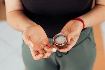 Vibhuti sacred ash in a copper container. Woman applying holy ash on her fingers.