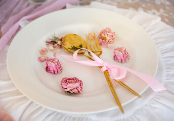 A white plate with a beautiful spoon and fork and flower petals.