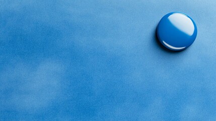 Single shiny blue button against a textured, light-blue surface