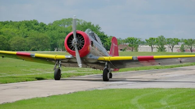 A propeller plane is ridding on the taking off lane at the small airport. Green, bright sunny summer day. 