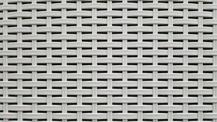 Close-up of woven plastic surface of laundry basket. Close-up of synthetic plastic pattern. Close-up of woven surfaces of plastic household baskets. Texture. Plastic rattan with symmetrical pattern