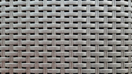 Close-up of woven plastic surface of laundry basket. Close-up of synthetic plastic pattern. Close-up of woven surfaces of plastic household baskets. Texture. Plastic rattan with symmetrical pattern