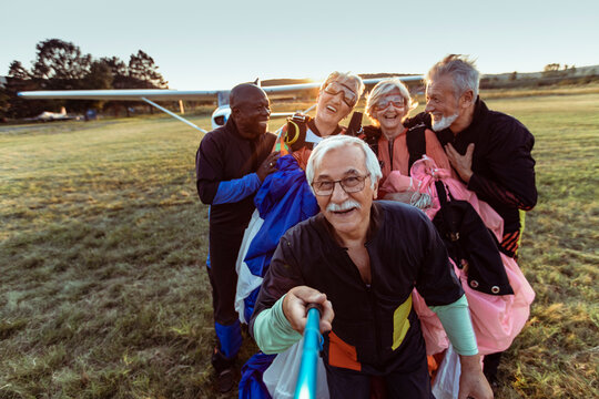 Group of senior people taking a selfie after skydiving on a field