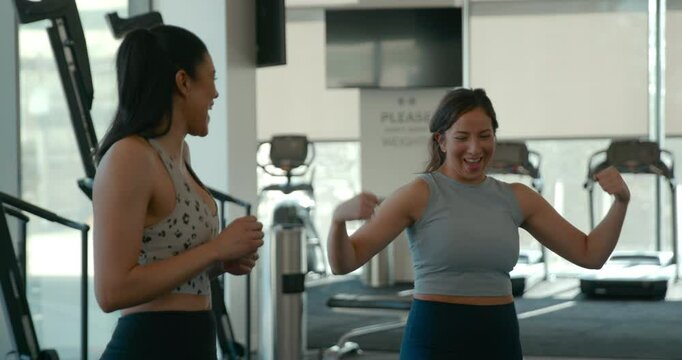 Athletic women laugh and flex biceps after a workout in a cross training gym