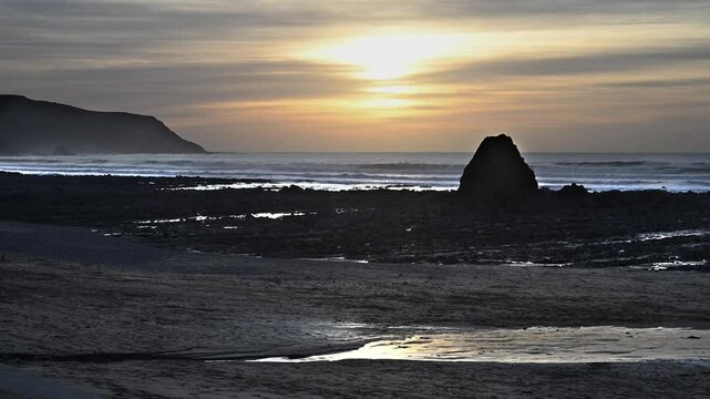 Spectacular winter sunset behing Cornwall Black Rock on Widemouth Bay