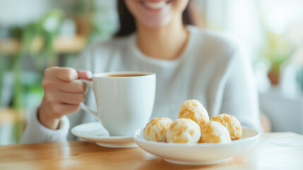 A happy Brazilian woman enjoying a warm cup of coffee with pÃ£o de queijo for breakfast at home, savoring the delicious start to her day. Concept of cozy mornings and traditional Br