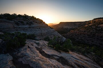 Obraz premium Dramatic sunset over rugged canyon landscape with textured rock formations