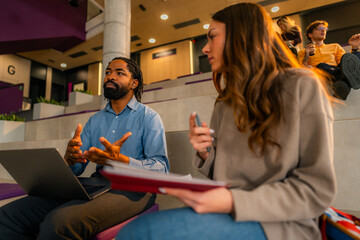 University professor explaining lesson to student with laptop and notebook