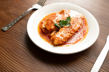 Bluefish with tomato sauce and olive oil served on a white plate in Mediterranean style