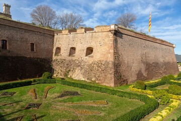 Green Garden and Montjuic Castell or Castle Old Catalan Military Fortress, Famous Catalan Tourist Attraction. Blue Skyline Sunny Day Barcelona Spain