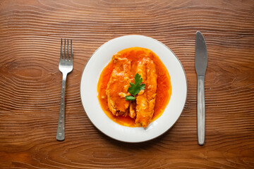 Bluefish with tomato sauce and olive oil served on a white plate in Mediterranean style