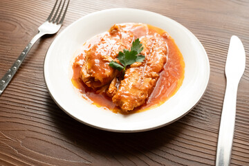 Bluefish with tomato sauce and olive oil served on a white plate in Mediterranean style