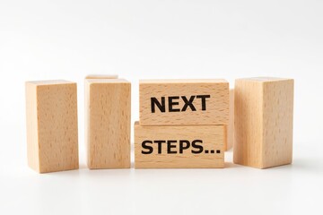 A wooden building blocks arranged against a white background. One block prominently displays the text NEXT STEPS.