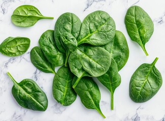 Obraz premium Sage green, fresh spinach leaves on a white marble background, in a flat lay, top view. Stock photo contest winner, food photography, stock photo, award-winning, high resolution, high detail, colorful