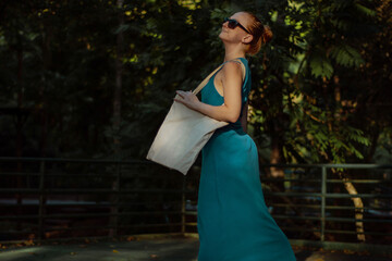 woman walking in the park in a blue dress holding a sustainable ecobag